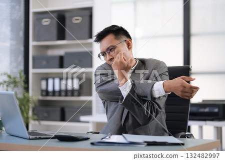 Male businessman is doing a stretchy posture due to sitting in the office for too long, office syndrome concept. 132482997