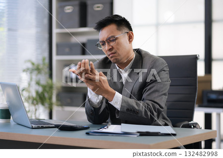 Male businessman is doing a stretchy posture due to sitting in the office for too long, office syndrome concept. 132482998