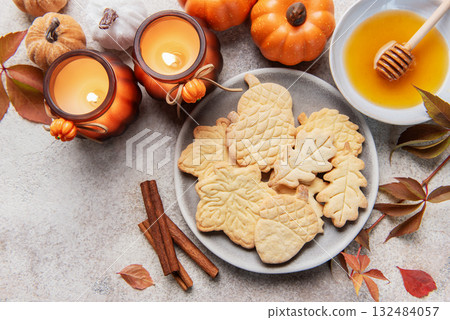 Autumn cookies, candles, pumpkins, honey, and cinnamon decorating table 132484057