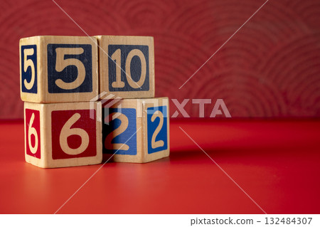 Stack of wooden number blocks with various numbers on a red background Stack of wooden number blocks with various numbers on a red background 132484307
