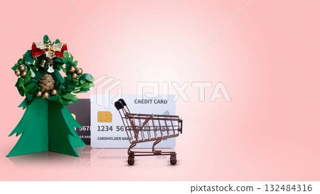 Shopping cart with credit card and Christmas tree ornament on colored background. Copy space. Christmas sale concept 132484316