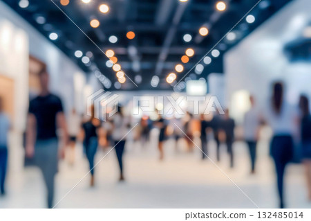 Crowd of visitors walking through a bustling exhibition hall, engaged in exploring different stalls and interacting with displays 132485014