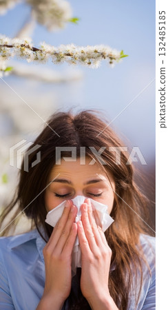 Woman sneezing into tissue during spring allergy season 132485185