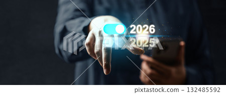 Business hand with cellphone touching the year 2026 above 2025 on a virtual screen. Happy New Year concept or Celebration 132485592