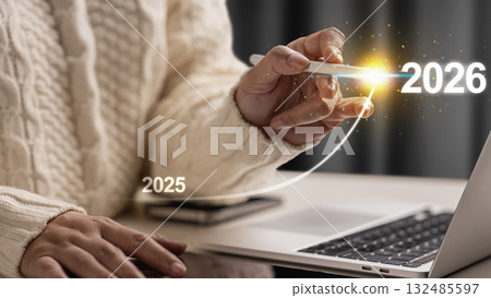 Female hand with laptop and cellphone slides the ascending line from 2025 to 2026 on a virtual screen. Happy New Year concept or Celebration Female hand with laptop and cellphone slides the ascending line from 2025 to 2026 on a virtual screen. Happy New Year concept or Celebration 132485597