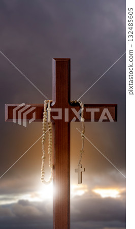 Christian cross and rosary beads with landscape view and dark dramatic sky background. Concept of Christianity, religious, faith, Jesus, or belief 132485605
