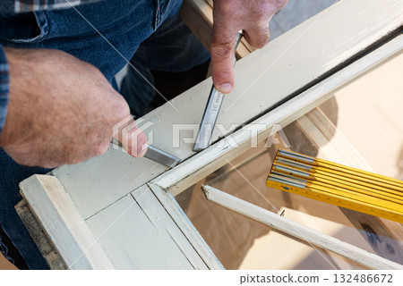 Carpenter at work, restoring an old wooden window. Carpentry. Carpenter at work, restoring an old wooden window. Carpentry. 132486672