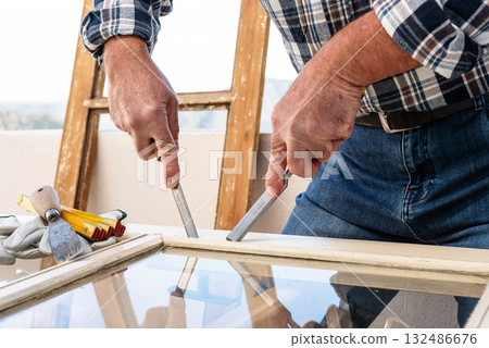 Carpenter at work, restoring an old wooden window. Carpentry. 132486676