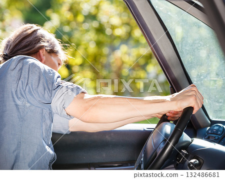 Young man with long hair driving car Young man with long hair driving car 132486681