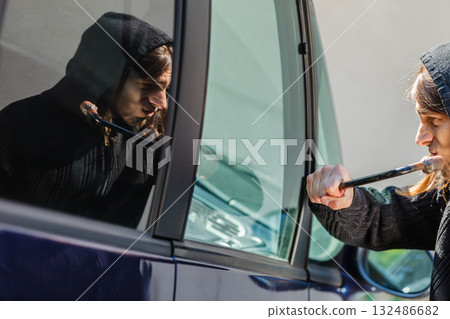 Thief burglar breaking smashing the car window Thief burglar breaking smashing the car window 132486682