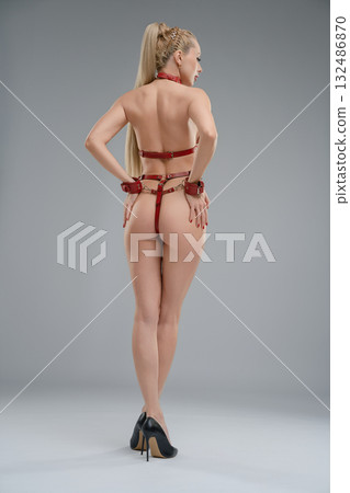 Woman posing in leather belts in a studio setting with a focus on style and fashion 132486870