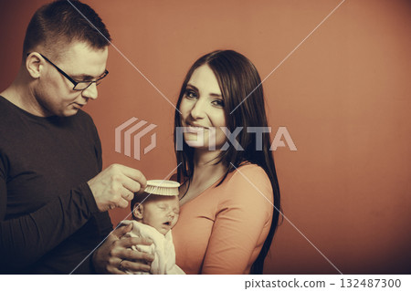 Newborn on mother chest, father brushing baby hair 132487300