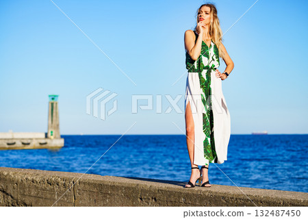 Woman in summer long dress against sea Woman in summer long dress against sea 132487450