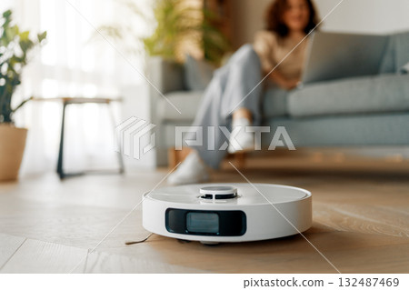 White robotic vacuum cleaner on wooden floor 132487469