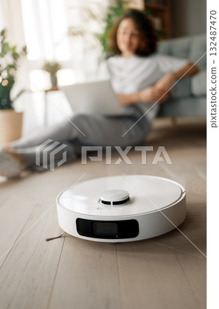 White robotic vacuum cleaner on wooden floor 132487470