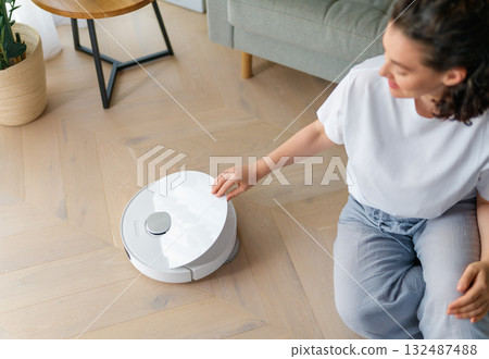 White robotic vacuum cleaner on wooden floor 132487488