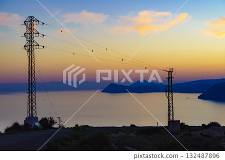 High voltage towers on coast at sunset 132487896