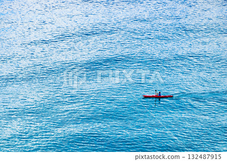 Person kayaking on blue sea. Person kayaking on blue sea. 132487915