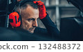 Racing engineer wearing earmuffs in garage preparing 132488372