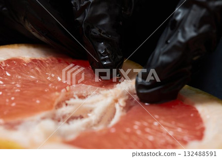 Half of grapefruit with vertical barbell piercing on a background. 132488591