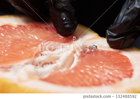 Half of grapefruit with vertical barbell piercing on a background. Half of grapefruit with vertical barbell piercing on a background. 132488592