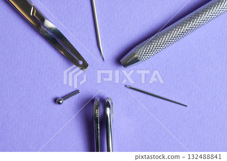Piercing earrings close-up. On a Violet background. 132488841