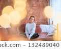 fragile teenage girl in bed hugging pillows surrounded by golden Christmas lights 132489040