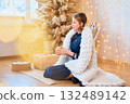 teenage girl in a dress near an unconventional Christmas tree surrounded by golden lights 132489142