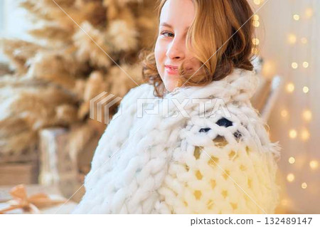 teenage girl in a dress near an unconventional Christmas tree surrounded by golden lights 132489147