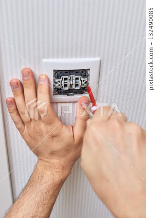 electrician working on light switch using screwdriver inside, close-up electrician working on light switch using screwdriver inside, close-up 132490085