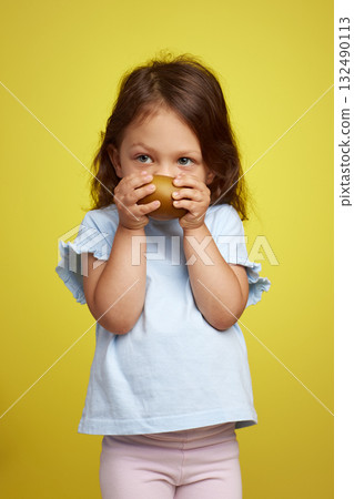 cute Caucasian little child girl holding kiwi fruit on yellow background cute Caucasian little child girl holding kiwi fruit on yellow background 132490113