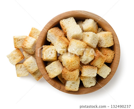 Bread croutons in a wooden plate and scattered close-up on a white. Top view 132490237