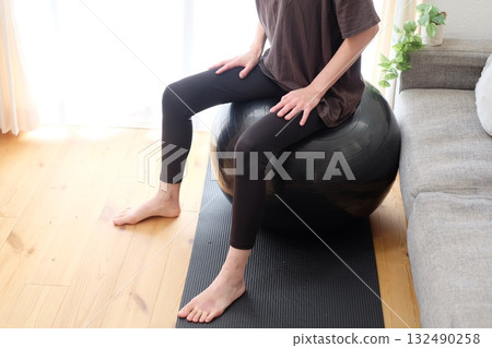 一位 40 多歲的女性坐在平衡球上 一位 40 多歲的女性坐在平衡球上 132490258