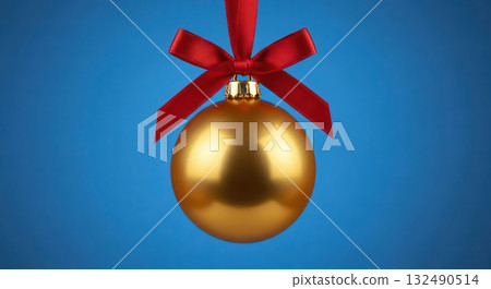 Golden Christmas ornament with a red ribbon hanging against a vibrant blue background, symbolizing festive spirit and holiday celebrations, perfect for seasonal decorations and promotions 132490514