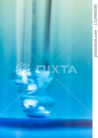Smudgy close-up photo of a dropper with air bubbles inside a blue glass bottle. Concept of cosmetic, skincare, serum, product detail, texture, realism, imperfection, beauty photography. Smudgy close-up photo of a dropper with air bubbles inside a blue glass bottle. Concept of cosmetic, skincare, serum, product detail, texture, realism, imperfection, beauty photography. 132490598