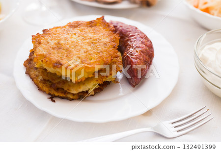 Potato pancakes with fried sausage on white plate Potato pancakes with fried sausage on white plate 132491399