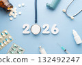 2026 Happy New Year banner for health care and medical concept. Stethoscope with doctor pills, syringe, vaccine vial, eyes drop, antibiotics and white number 2026 on table blue background. 132492247