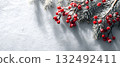 Bright red berries and pine branches on a snowy surface create a festive winter scene 132492411
