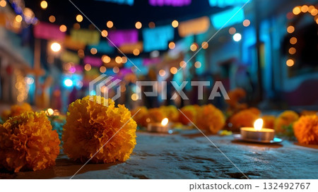 Colorful marigolds and candles adorn an altar for Dia de Muertos. The vibrant street is illuminated with festive lights and papel picado decorations. 132492767
