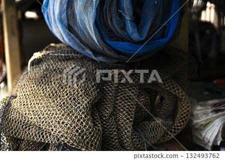 Old Fish Cage Net Rolled Up and Unused, An aged fish cage net rests rolled up, dusty fibers in muted light, great for a historical photo session or a neglected fishery exhibit. Old Fish Cage Net Rolled Up and Unused, An aged fish cage net rests rolled up, dusty fibers in muted light, great for a historical photo session or a neglected fishery exhibit. 132493762
