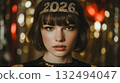 A young Caucasian woman with short brown hair wears a sparkling headband with '2026'. She has a neutral expression and is surrounded by festive, colorful lights. 132494047