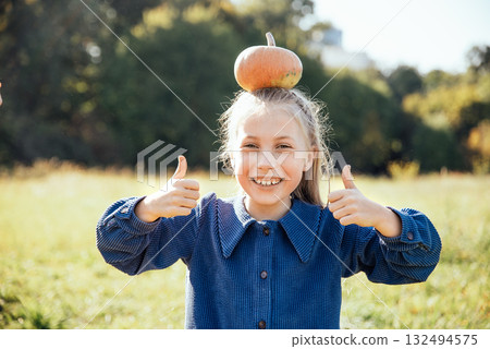 Autumn harvest organic pumpkins and apples. Happy girl on pumpkin patch on cold autumn day, with lot of pumpkins for halloween or thanksgiving Children on pumpkin field. Autumn harvest organic pumpkins and apples. Happy girl on pumpkin patch on cold autumn day, with lot of pumpkins for halloween or thanksgiving Children on pumpkin field. 132494575