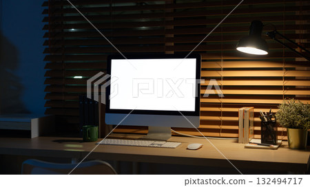Computer on desk in peaceful nighttime workspace with office supplies 132494717