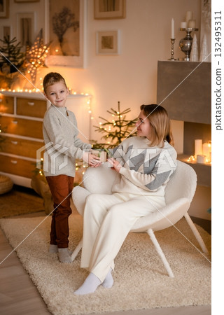 Child Giving Holiday Gift to Parent in Cozy Room Child Giving Holiday Gift to Parent in Cozy Room 132495311