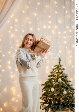 Woman Holding Gift Boxes by Christmas Tree Woman Holding Gift Boxes by Christmas Tree 132495323