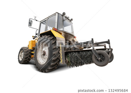 A tractor equipped with a large sweeper brush against an isolated background. Cleaning city roads of dust and debris. Equipment rental. A tractor equipped with a large sweeper brush against an isolated background. Cleaning city roads of dust and debris. Equipment rental. 132495684
