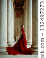 A woman in a red dress stands in front of a marble pillar 132497273