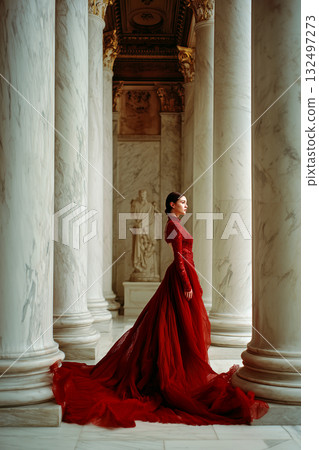 A woman in a red dress stands in front of a marble pillar 132497273