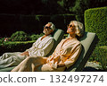 A man and a woman are sitting on a lawn chair, both wearing sunglasses 132497274