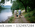 Two people walking along a path by a river, one of them holding a green cooler 132497284